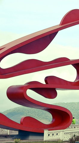 a-large-red-sculpture-sitting-on-top-of-a-lush-green-field.jpg a large red sculpture sitting on top of a lush green field